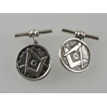 A pair of white metal cufflinks, the disc cast with Masonic symbols on a bar and chain.