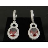 A pair of cubic zirconia and simulated ruby drop earrings.