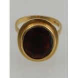 An 18 carat yellow gold and oval cut garnet ring.