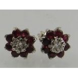 A pair of white metal and ruby stud earrings.