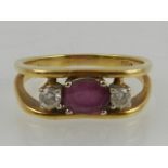 A yellow metal, diamond, and ruby ring, the openwork angular mount set with an oval cut ruby,