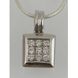 An 18 carat white gold and diamond set pendant, suspended on a silver chain.
