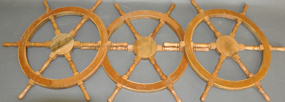 Three hardwood six spoke decorative ship's wheels, D. 65cm, (3).