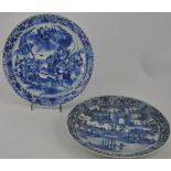 A pair of Chinese blue and white plates, one decorated with a view of a wall city beside a lake,