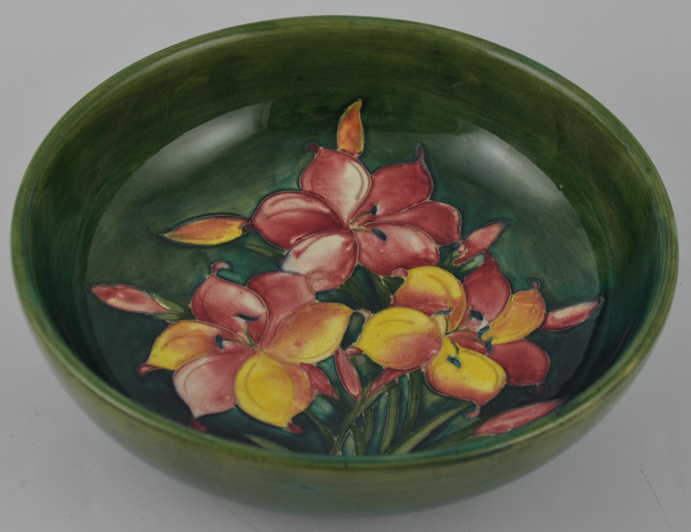 A Moorcroft circular pottery bowl, decorated with yellow and red Lillies on a mottled green body,