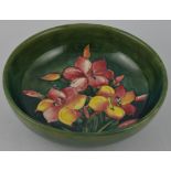 A Moorcroft circular pottery bowl, decorated with yellow and red Lillies on a mottled green body,