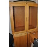 A beech display cabinet, the upper section with glazed panel doors, the base with cupboard doors, H.
