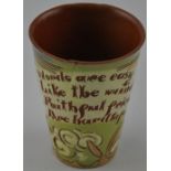 A Brannam Pottery beaker with sgraffito design and bearing a motto, H. 10cm.