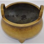 A Chinese bronze incense burner of caldron form with twin handles and raised on three short pointed