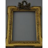 A small gilt picture frame, rectangular with projecting square corners and a trophy surmount,