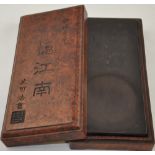 A Chinese rectangular ink stone, within a hardwood effect box, W. 25cm.