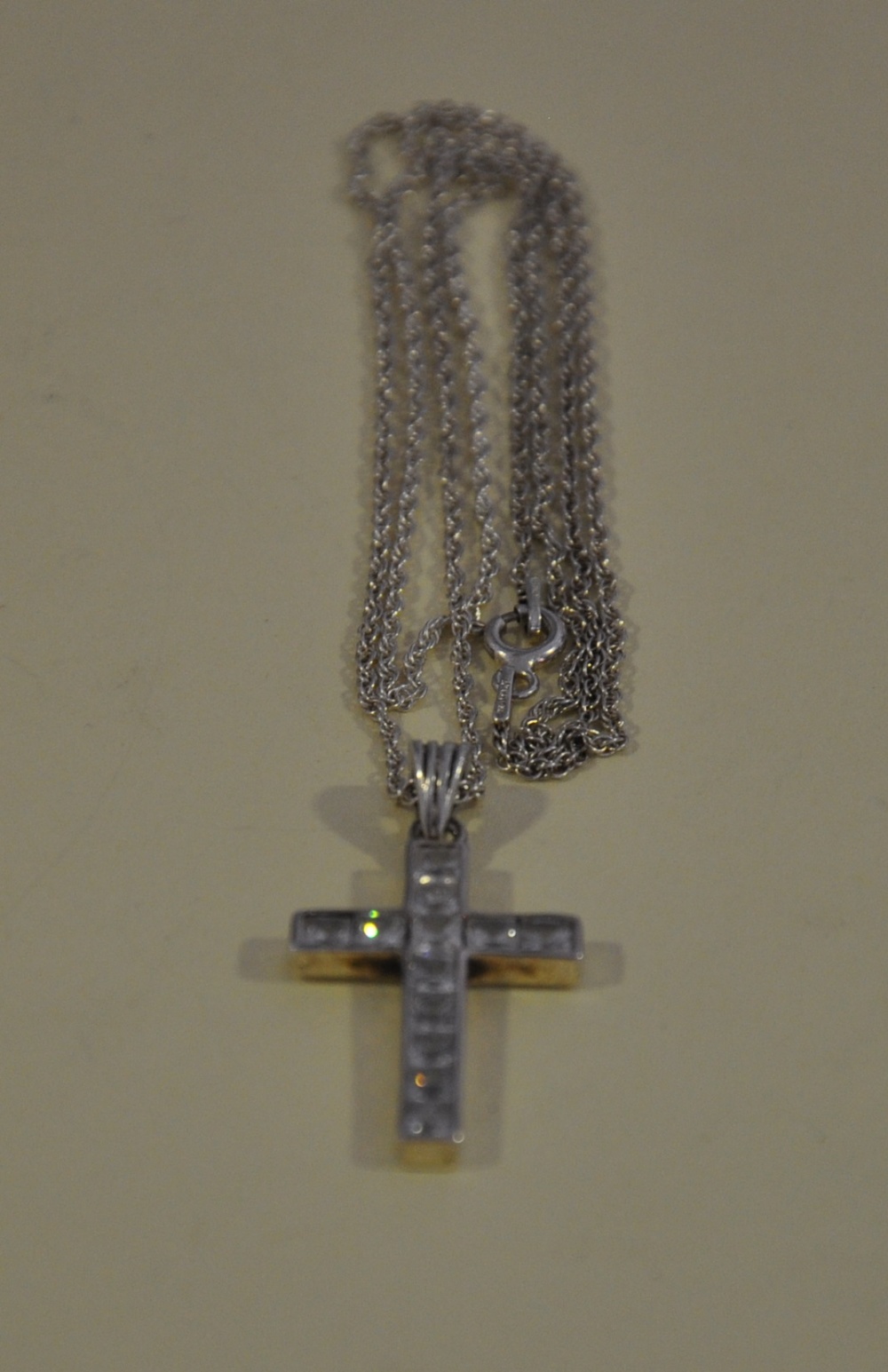 A white metal cross set with clear stones, stamped 925, on a fine chain.