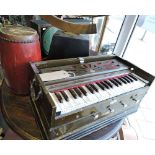 A Bina harmonium, the case with white metal brackets and carrying handles,