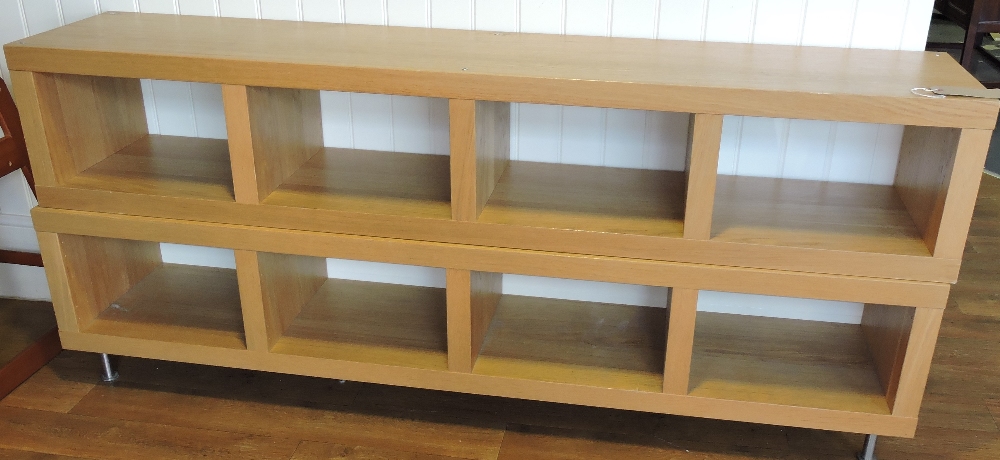 A low oak display cabinet, rectangular with square apperatures, raised on short brushed steel feet,