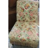 A late Victorian upholstered nursing chair, covered in a floral fabric, on short turned legs.