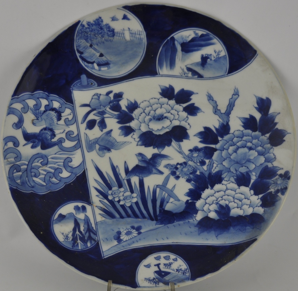 A large Chinese blue and white charger, decorated with flowers and vignettes on a dark blue ground,
