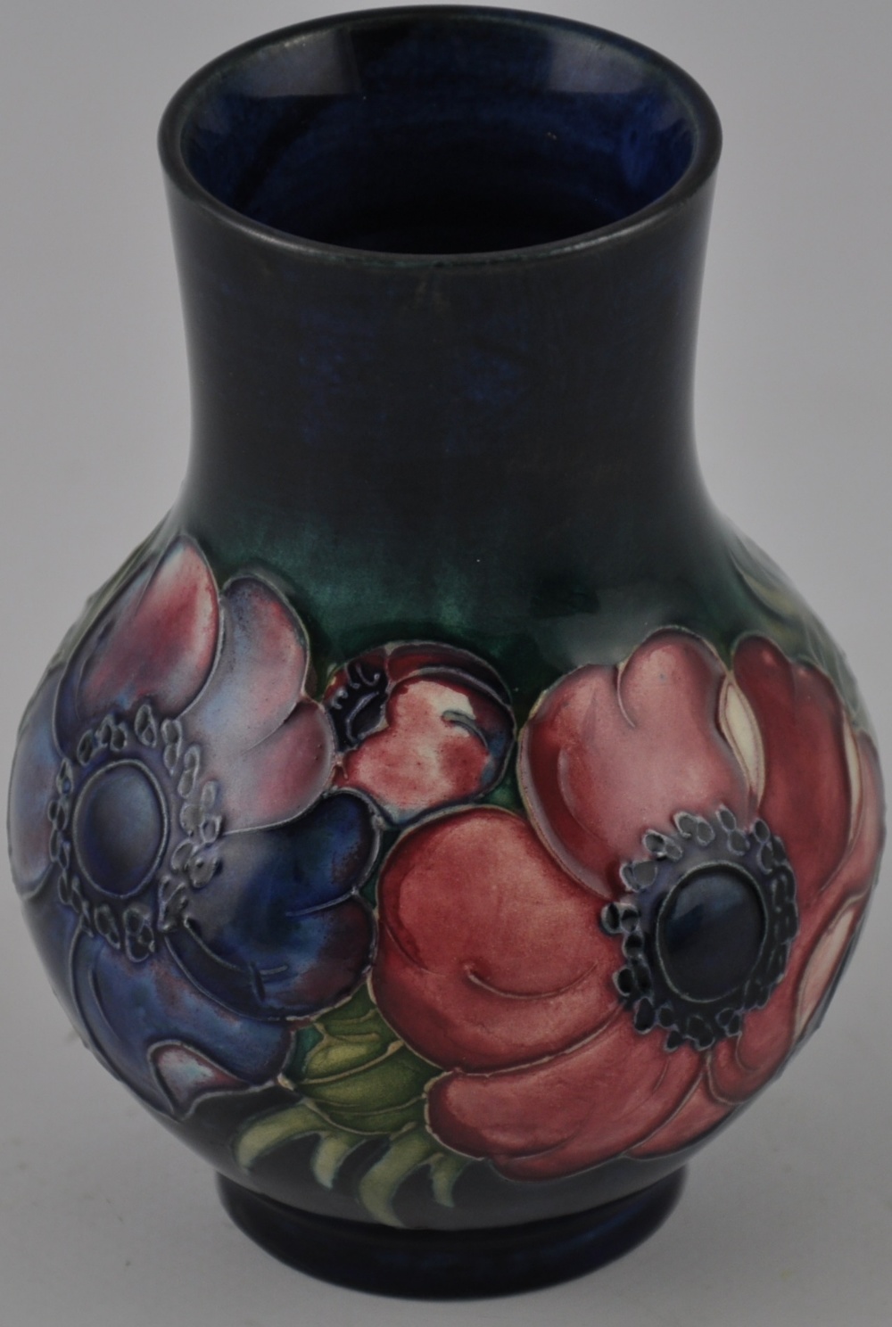 A Moorcroft pottery baluster vase, decorated with a band of Anemone on a mottled blue body,