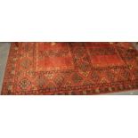 A Turkaman style brick ground rug woven with geometric devices,