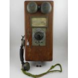 An early 20th century wall telephone mounted with wooden box, having instructions label to front.