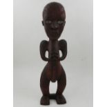 A Maori hardwood carved figure of a seated male.