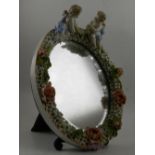 In the style of Meissen. A porcelain easel mirror, mounted with two cherubs.