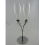 A pair of Moet Chandon 'Lovers' champagne flutes, with a cast metal stand, H. 30cm.