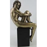 An Art Deco style bronzed composition figure of a seated female nude,