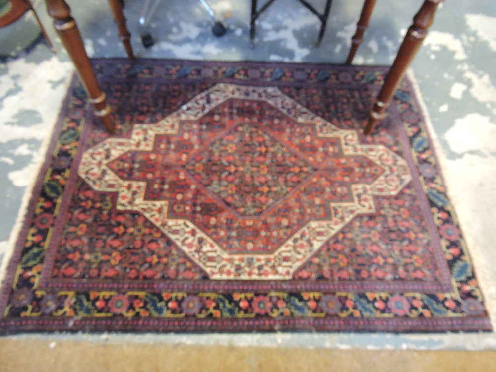 A Persian rug, with a central serrated motif within a white ground border, 142 x 106cm.