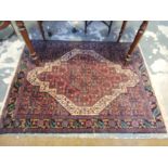 A Persian rug, with a central serrated motif within a white ground border, 142 x 106cm.