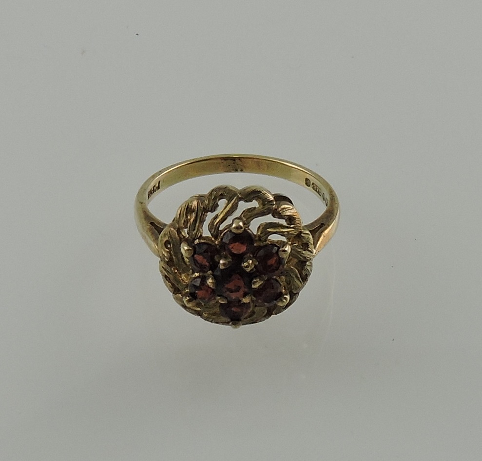 A garnet dress ring, in a pierced and domed yellow metal setting, 3.7g.