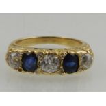 A yellow gold, diamond, and sapphire five stone ring, set two oval cut sapphires and three round cut