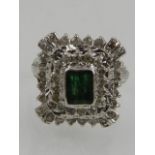 A white metal, diamond, and emerald set cocktail ring,
