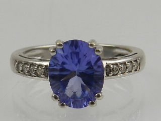 An 18 carat white gold, diamond, and tanzanite ring, the oval cut tanzanite flanked by round cut