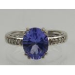 An 18 carat white gold, diamond, and tanzanite ring, the oval cut tanzanite flanked by round cut