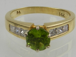A 14 carat yellow gold, diamond, and peridot ring, set central round cut peridot flanked by