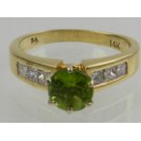 A 14 carat yellow gold, diamond, and peridot ring, set central round cut peridot flanked by