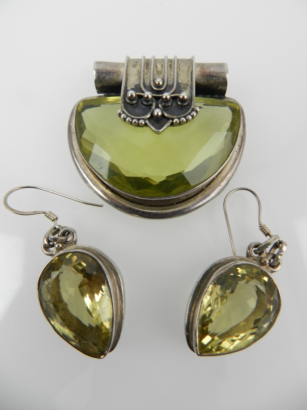 A white metal and gemstone pendant and earrings.