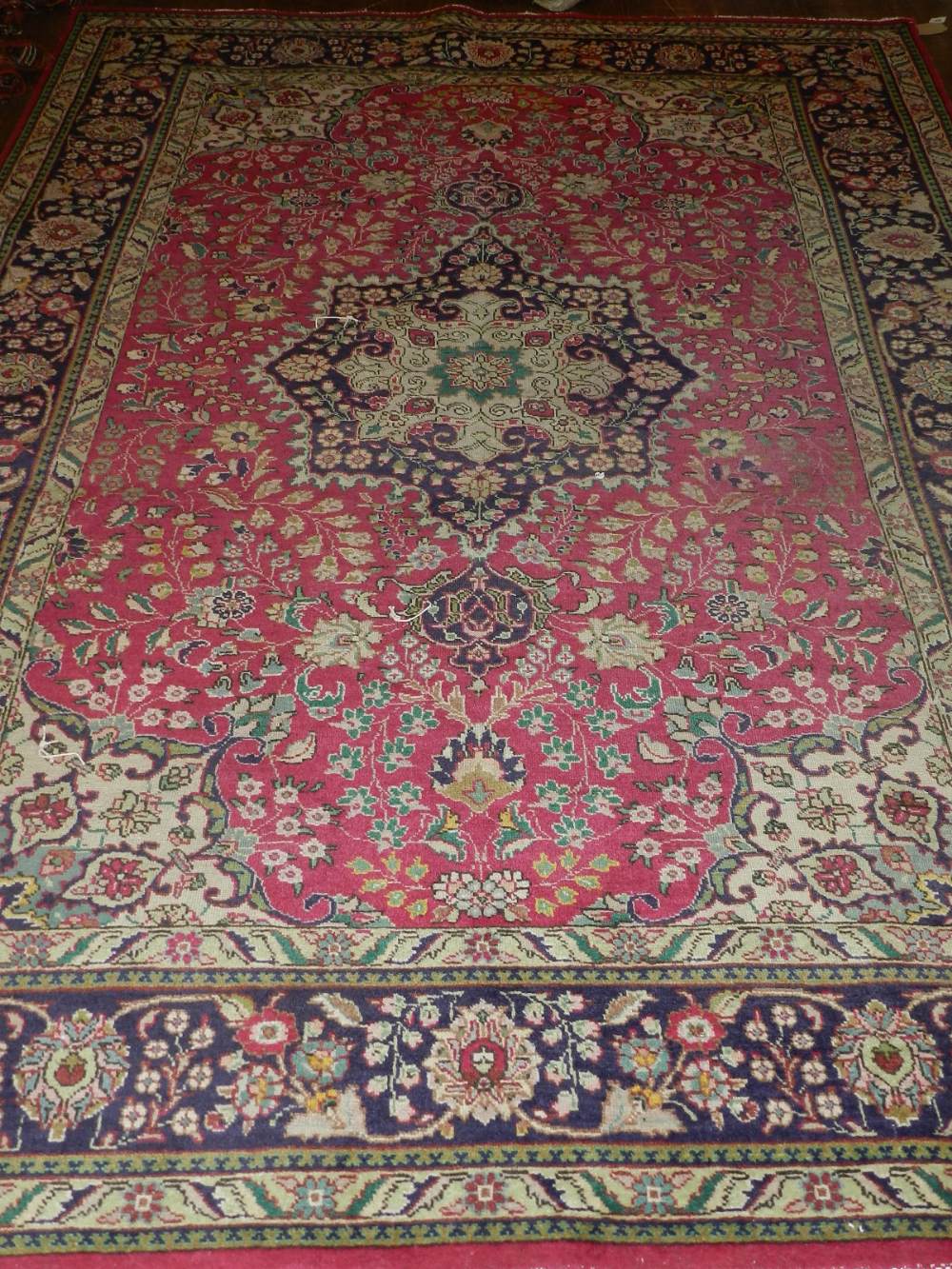 A Persian red ground Kashan rug, having hexagonal medallion to centre on a scrolling foliate ground,