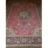 A Persian red ground Kashan rug, having hexagonal medallion to centre on a scrolling foliate ground,