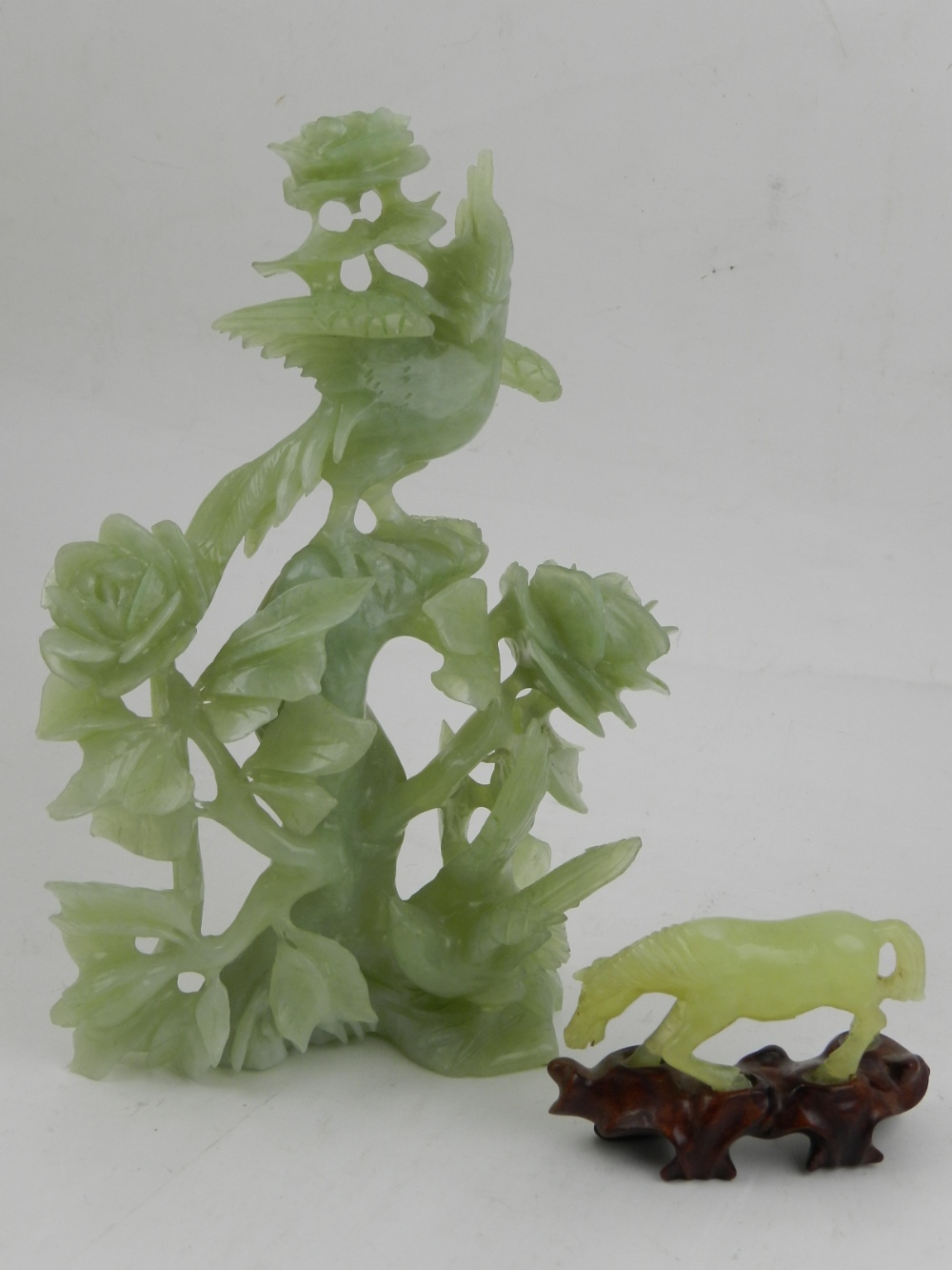 A Chinese carved green hardstone figural study of a bird amongst flowers and foliage,