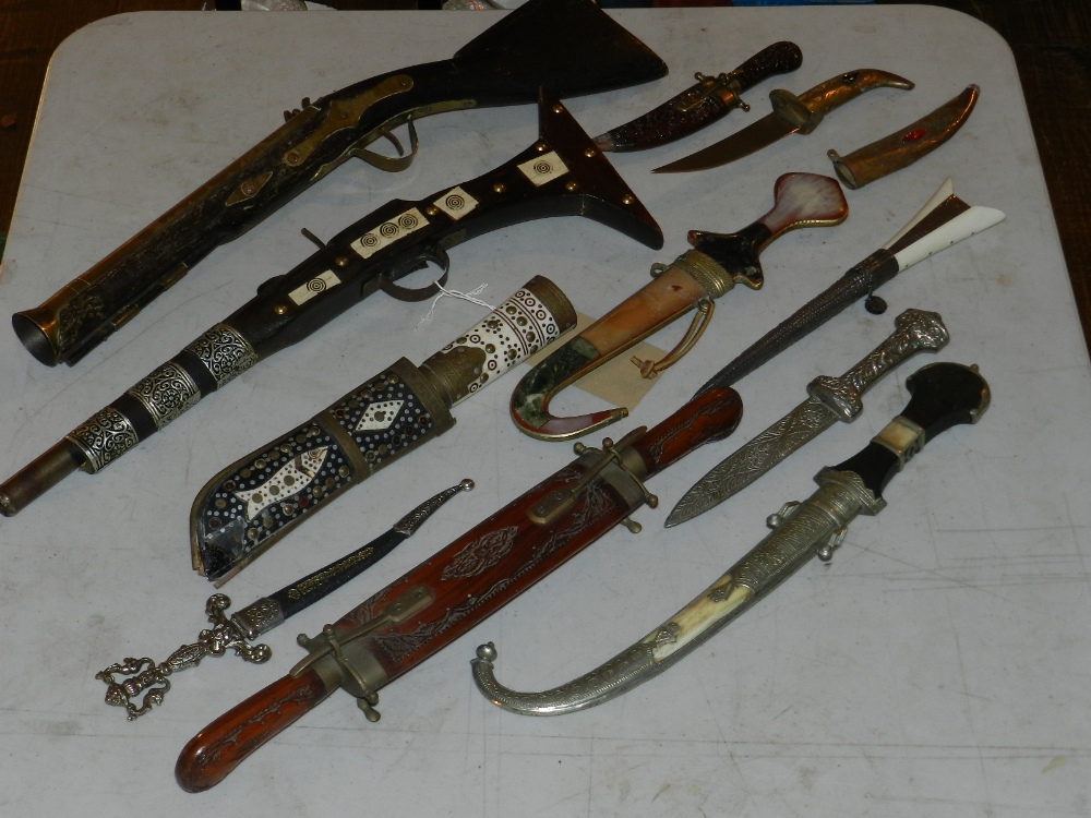 A selection of decorative daggers, a replica blunderbuss and a replica camel musket.