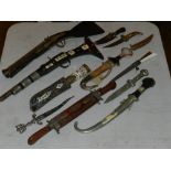 A selection of decorative daggers, a replica blunderbuss and a replica camel musket.