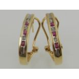 A pair of yellow gold, diamond, and ruby channel set half hoop earrings.