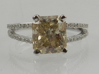 A white gold and diamond ring, set central princess cut central diamond, the shoulders set with