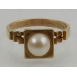 An unusual 9 carat yellow gold and pearl ring, in the Modernist taste.