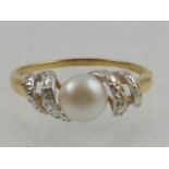 A 9 carat yellow gold, diamond, and button pearl ring.