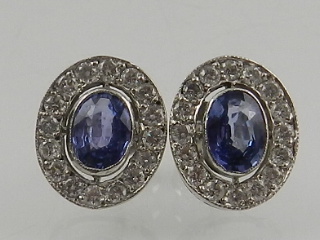 A pair of white gold, diamond, and sapphire oval cluster ear studs.