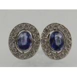 A pair of white gold, diamond, and sapphire oval cluster ear studs.