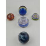 Two millefiori glass paperweights, one signed 1977, together with three other glass paperweights.