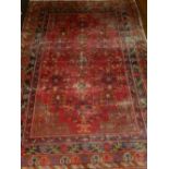 A South Persian red ground rug, having scrolling foliage to centre, within many borders, fringed. L.